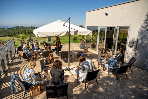 3 groupes de personnes sur la terrasse ensoleillée des Collines de Sainte-Féréole en train de déjeuner des plateaux-repas