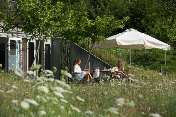 2 jeunes femmes en train de discuter autour d'une table sur la terrasse privative d'un gîte.